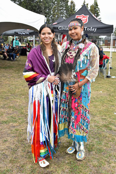 Two women smiling and dressed in Indigenous regalia