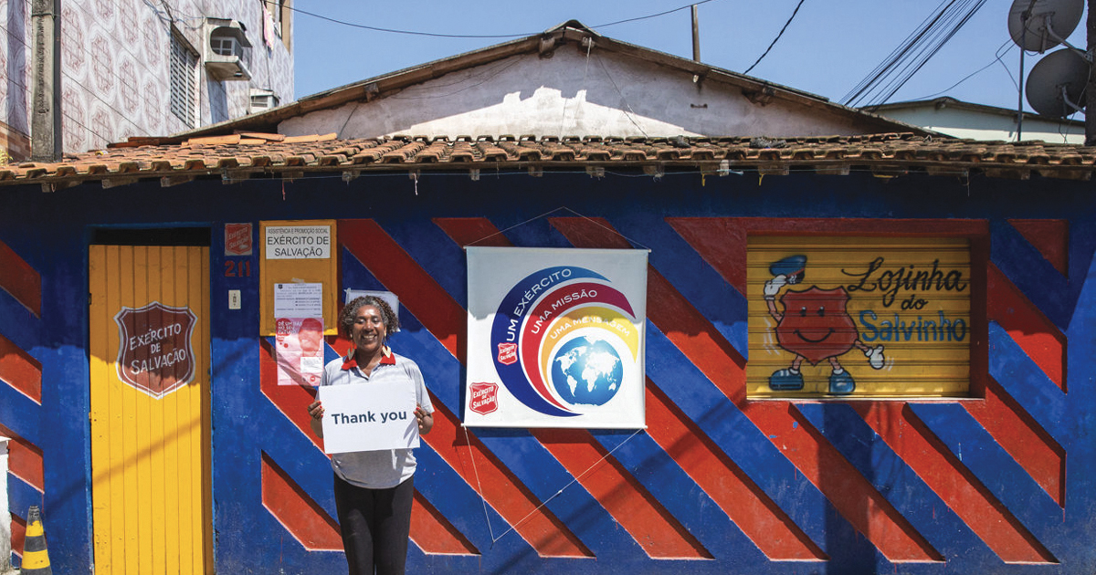 Sandra holds a sign that says "Thank you" in front of the Vila dos Pescadores children's program
