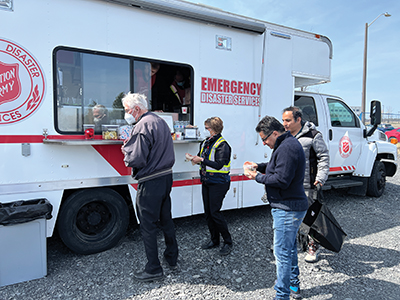 A group of people receive snacks from a Salvation Army Emergency Disaster Services truck