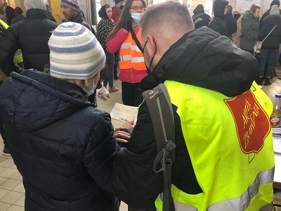 A Salvation Army worker and a refugee look at some documents together