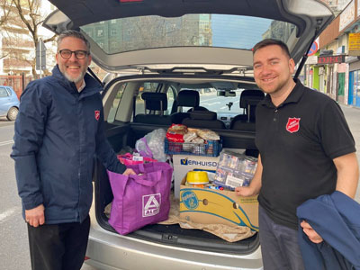 Two men stand by a car packed with supplies