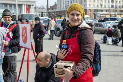 A woman wearing a Salvation Army apron serves food