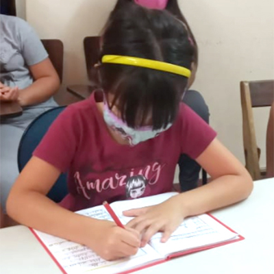 A girl sitting at a desk and writing 