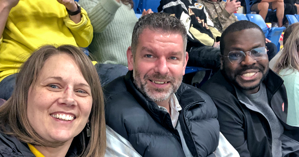  Cpts Jennifer and Rob Henson, with Lt Mark Cancia in the stands at a hockey game