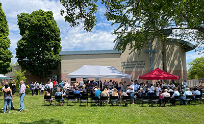 A large group of people sitting outside in a grassy area