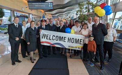 A group of people in an airport with a sign that says 