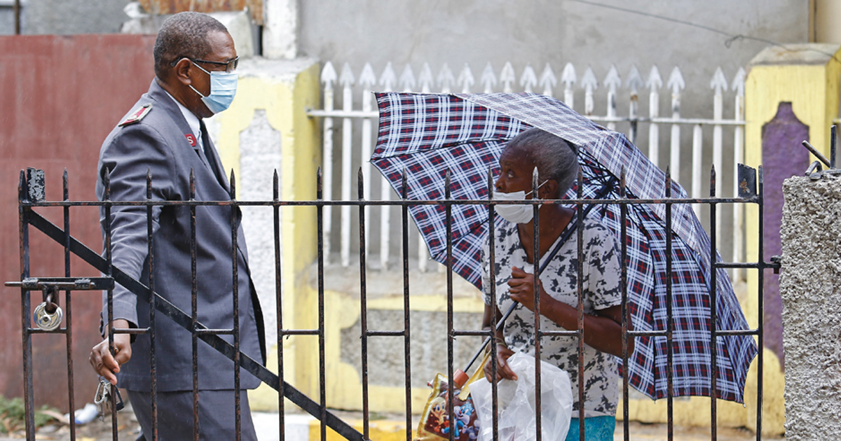 A Salvation Army officer talks to a woman holding an umbrella