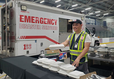 A Salvation Army worker stands next to a table ready to serve meals