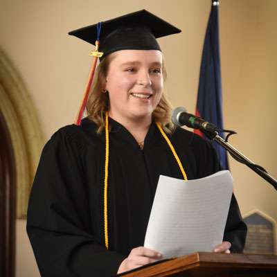 Young woman, in graduation robes, standing at a podium