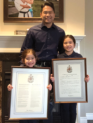 A man and two girls hold certificates