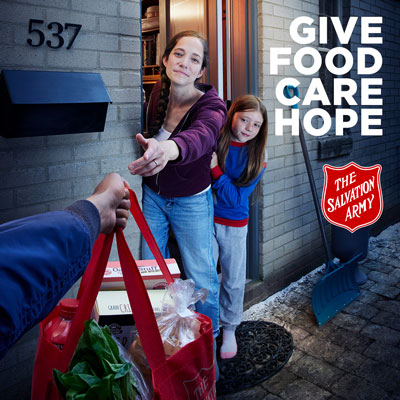 A woman and a young girl receive a bag of groceries from an outstretched hand