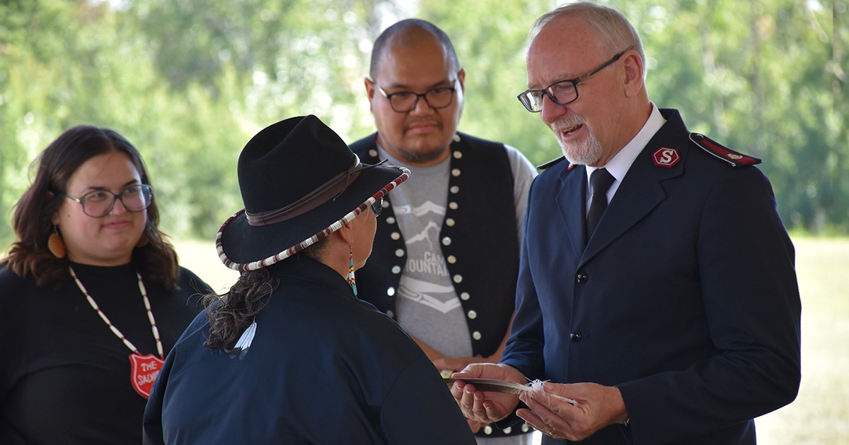 A man receives a feather from a woman while others look on