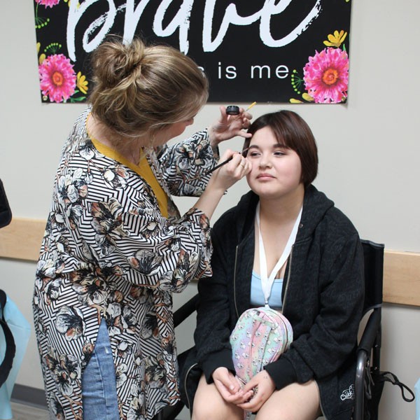 An older woman does the makeup of a young woman