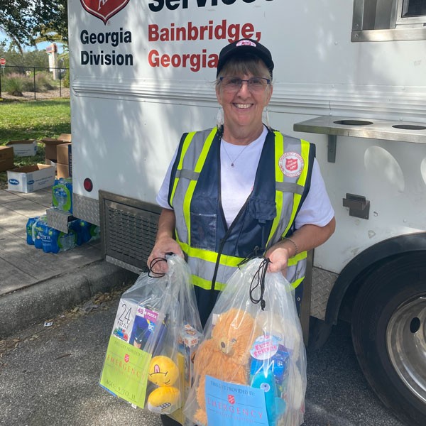 A woman holding bags of supplies by a canteen truck