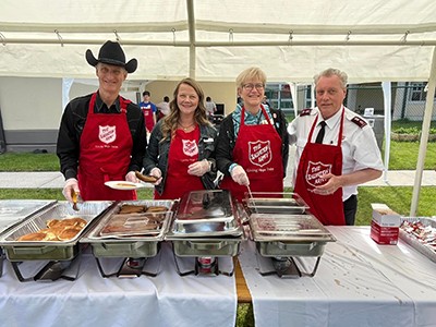 A group of people serve pancakes in an outdoor tent