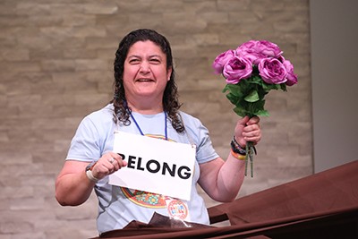 A delegate holds a bouquet of flowers and a sign that reads 