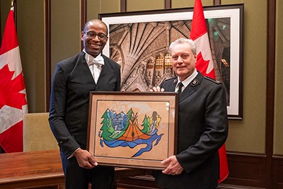 Greg Fergus receives a painting from Commissioner Lee Graves
