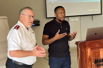 Two men stand together giving a presentation