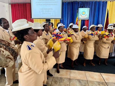 People in tan Salvation Army uniforms sing and play instruments during a church service