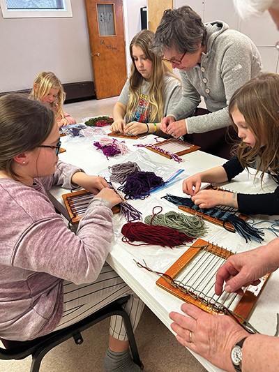  Kids try weaving on a pin loom 