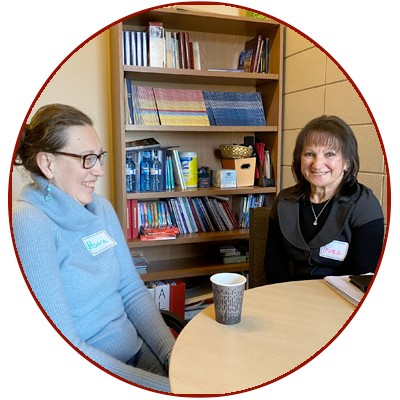 Anya (left) and Iryna (right) smile and talk over coffee