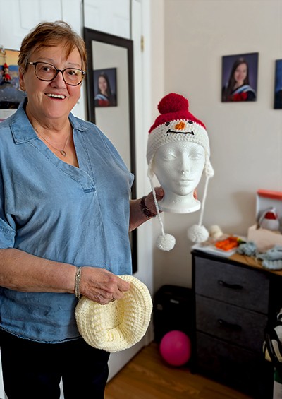 Hannam smiles and holds a crocheted snowman hat