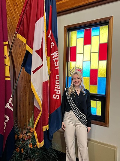 Grace Kelly stands in front of The Salvation Army flag.