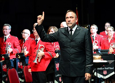 John Lam stands in front of the band and salutes