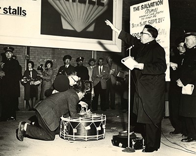 A man kneels at a Salvation Army drum during a meeting