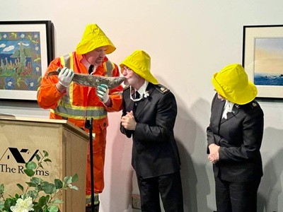 A man wearing a yellow hat kisses a fish