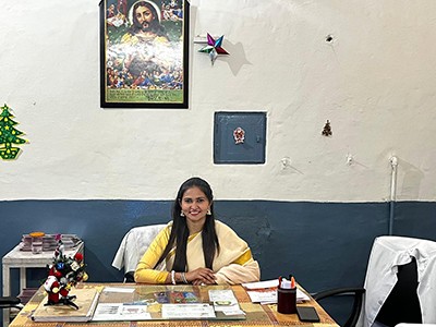 Kaur sits at a desk in the dental office at the Mac Robert Hospital