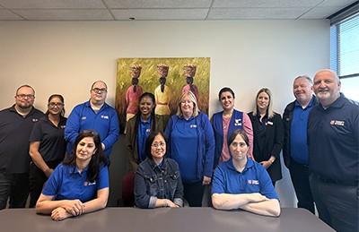 The NRO team poses in front of the photo purchased by the international development department at a Salvation Army thrift store in Burlington, Ont., last year