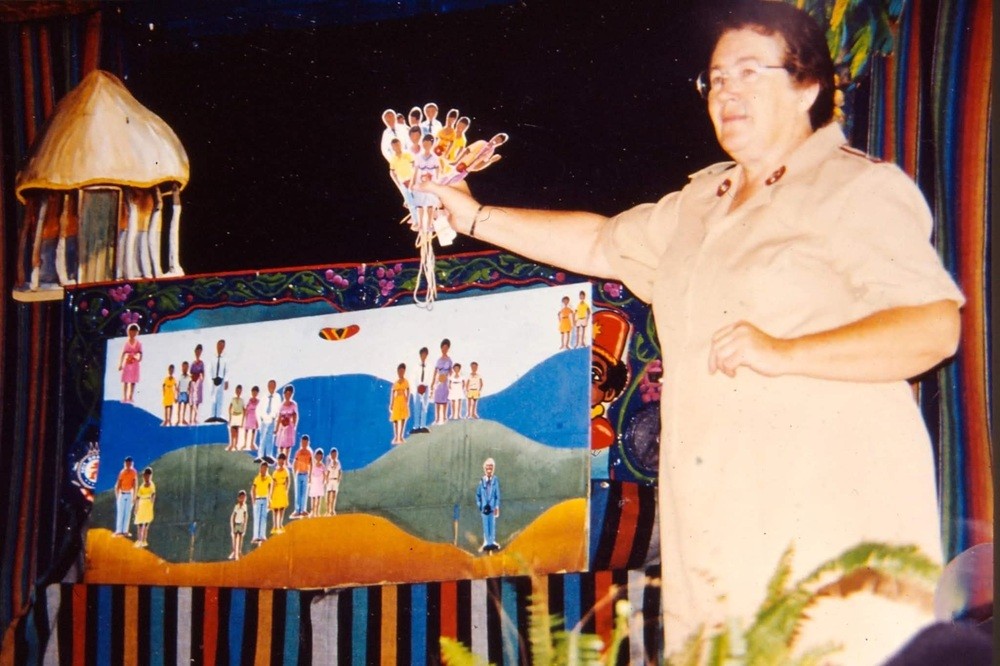 A woman holds up puppet figures, teaching a lesson