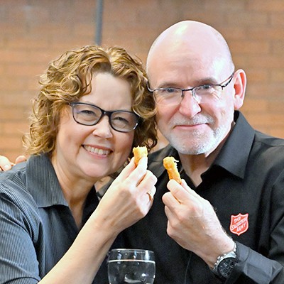 A woman and a man smile while holding a chicken nugget