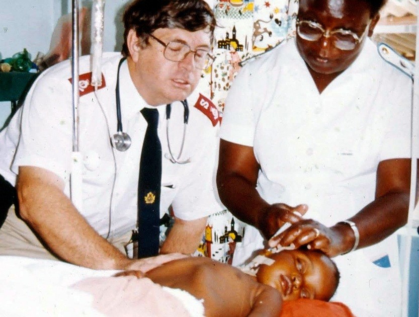 A man and woman examine a baby in a medical setting