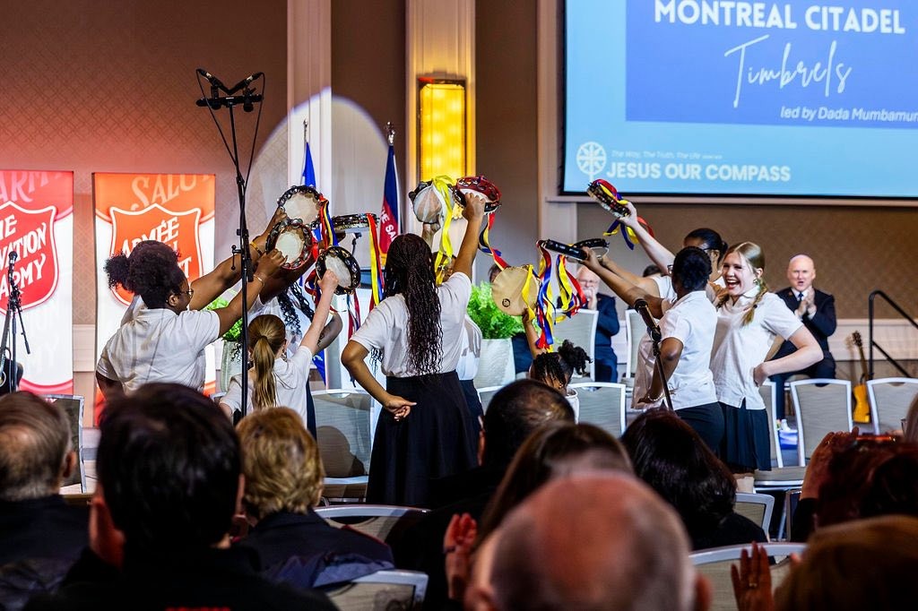 A group of young women at the front of a crowd waving tambourines