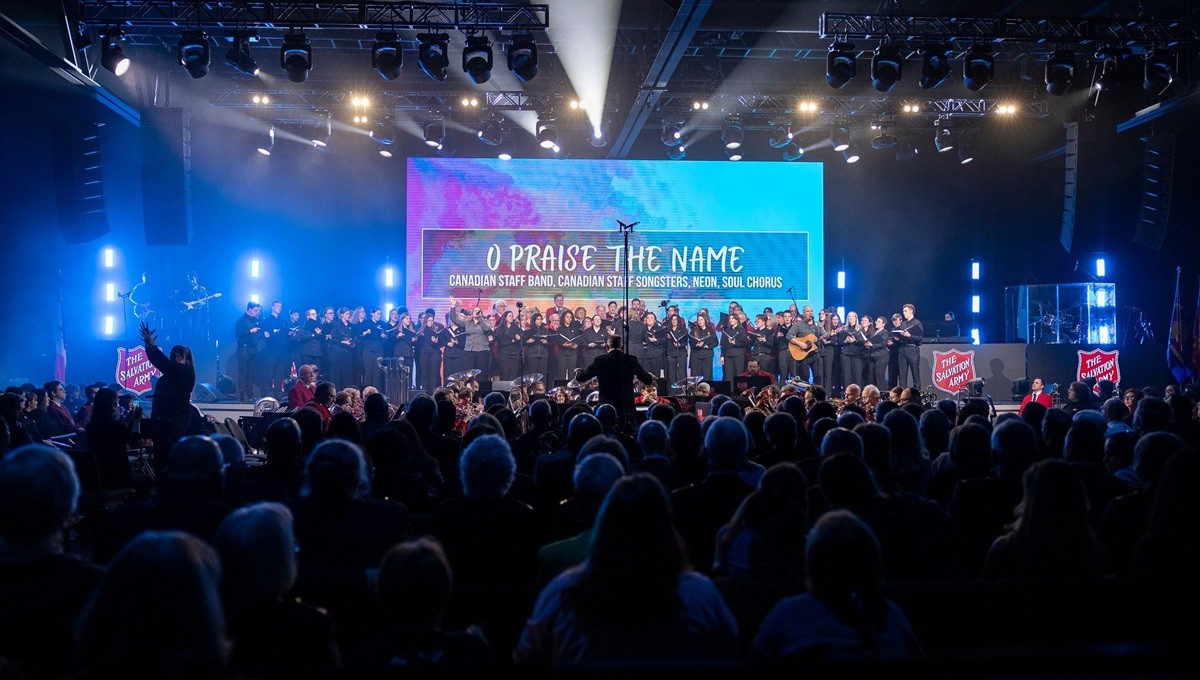 A choir performs on stage in a darkened auditorium