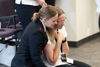 Two women sit together in prayer