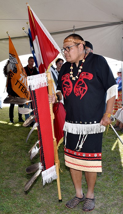 An Indigenous man leads a group of people in a tent