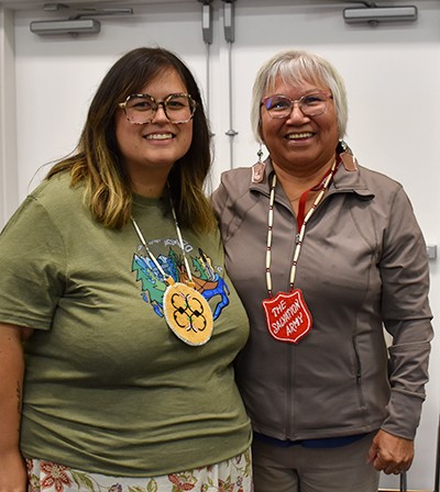 Two Indigenous women stand together smiling