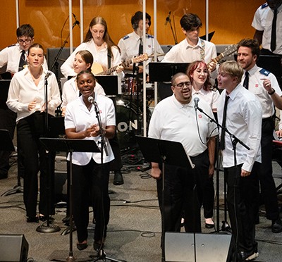 A group of young people sing and play instruments on a platform