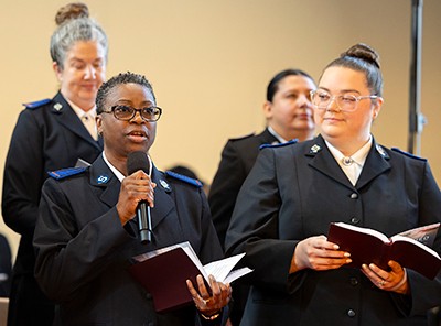 A woman speaks into a microphone while another looks on