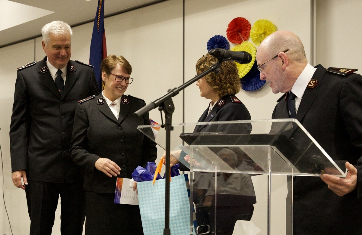 A man and woman present gift bags to another man and woman