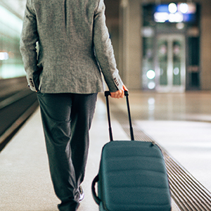 Image of a man in a business attire carrying his luggage at a station