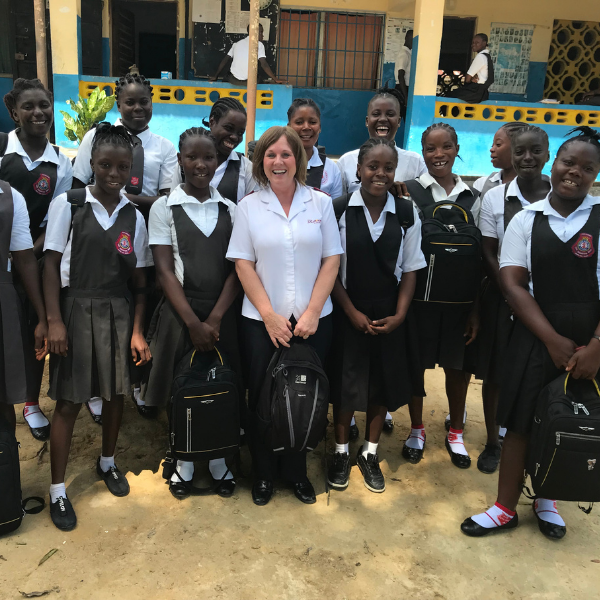 Smiling female students in Liberia standing alongside director of International Development