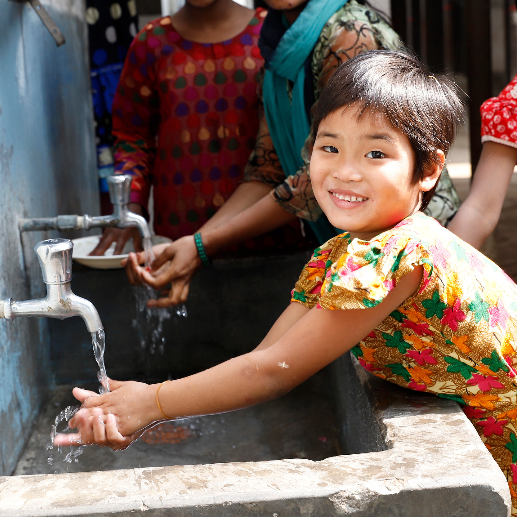 Photo of smiling girl in Bangladesh washing her hands