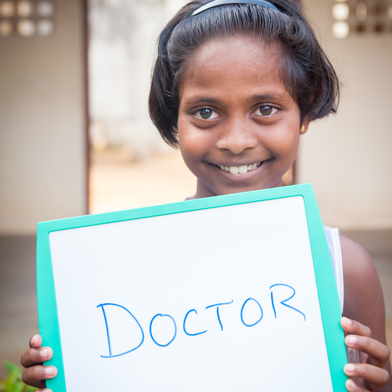 Photo of girl child from Sri Lanka holding up a sign that says she wants to be a doctor